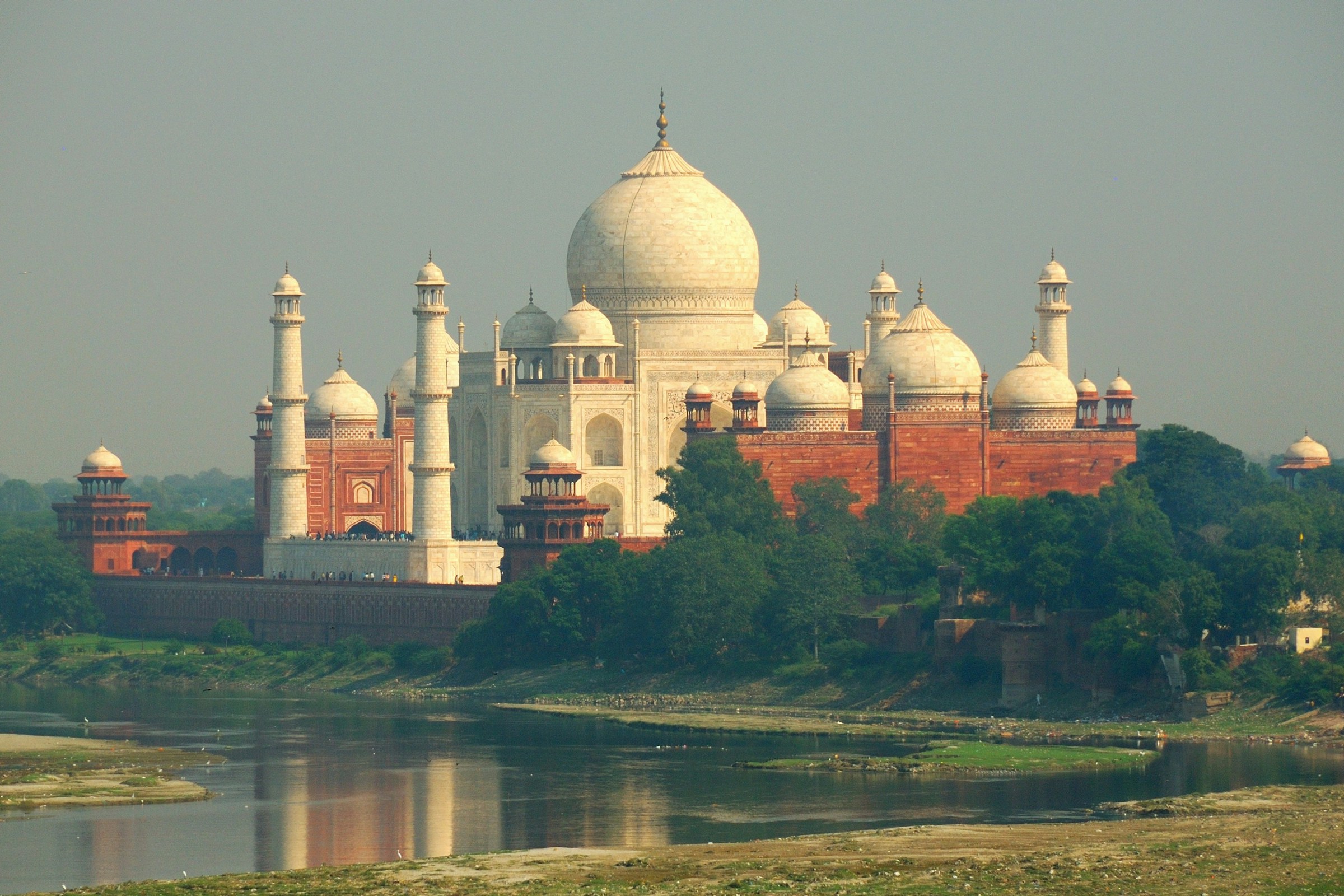 The Taj Mahal near a calm river at sunrise