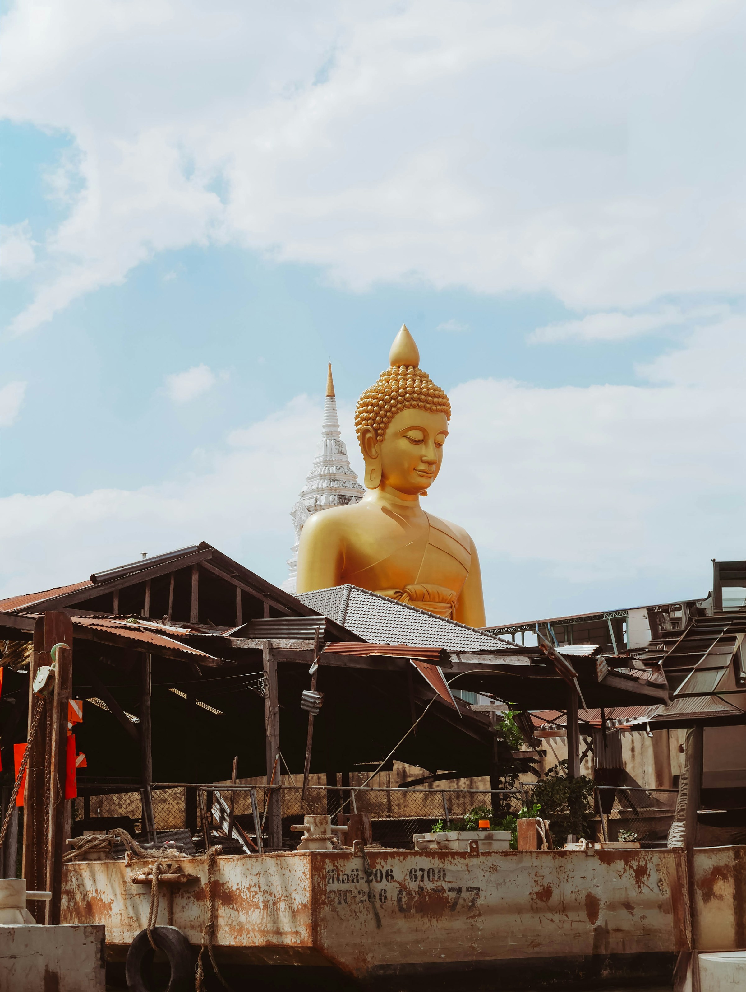 Golden Buddha statue towering over rustic buildings