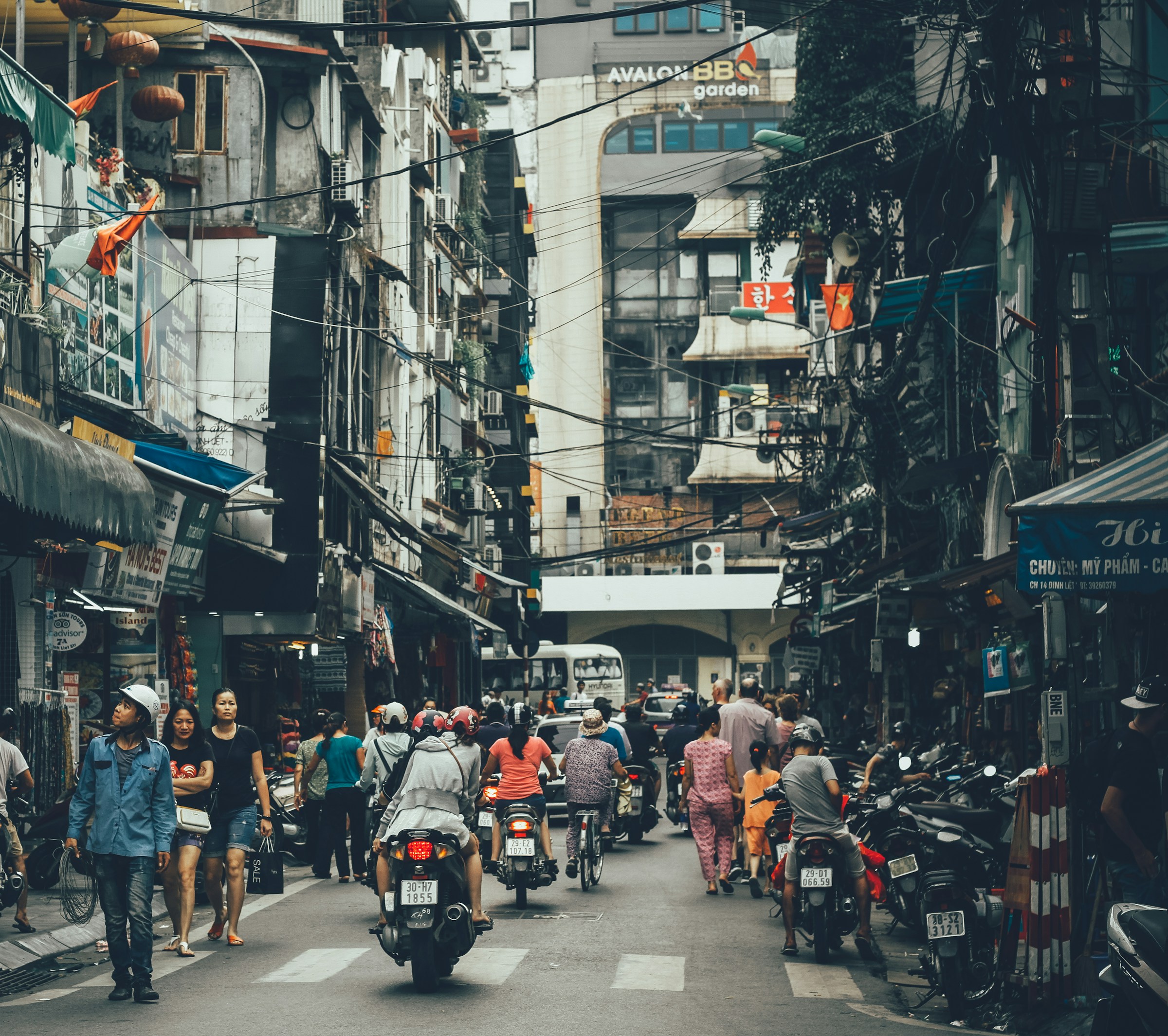 People walking a road between buildings, Hanoi Old Quarter