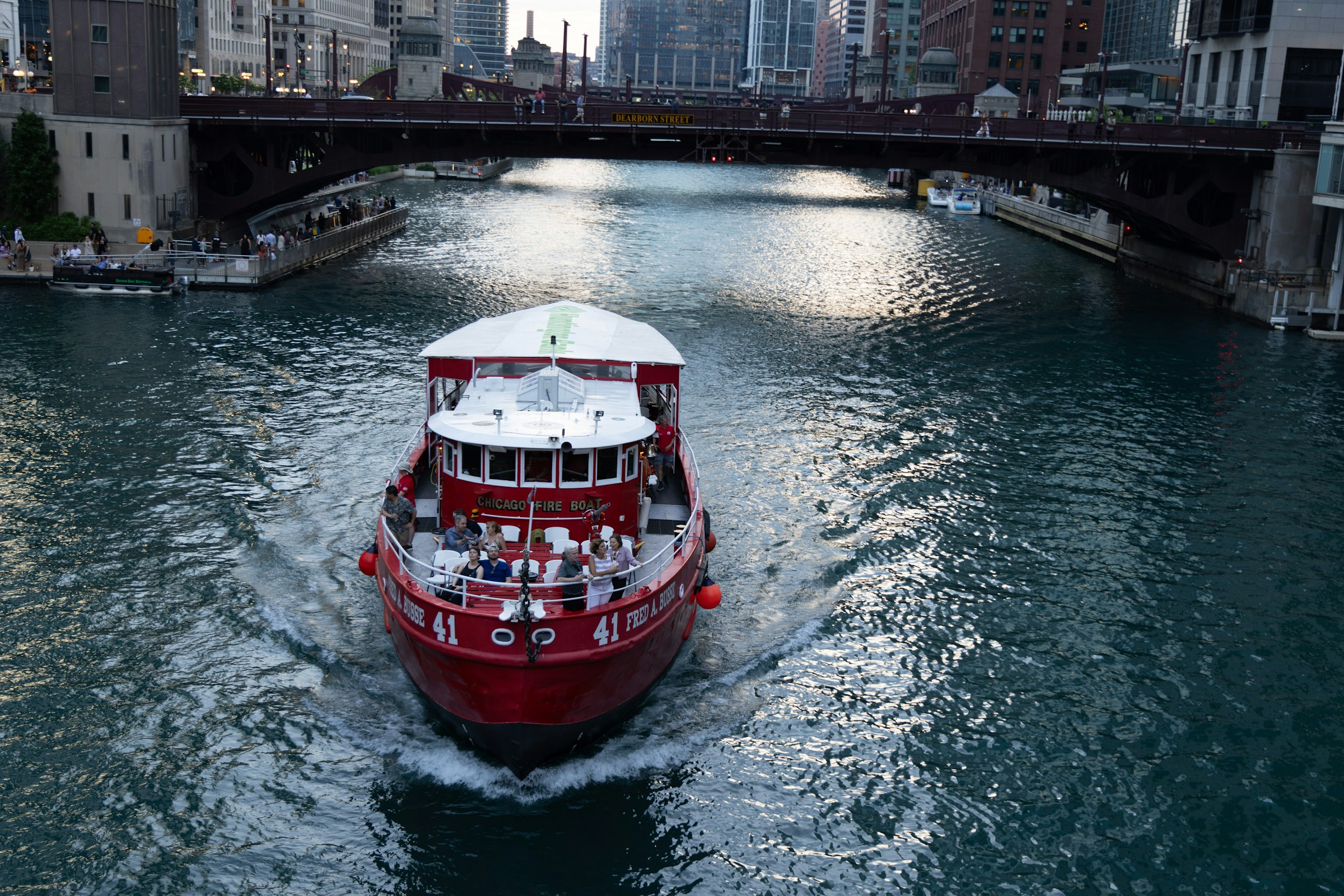 Red and white boat cruising a city river