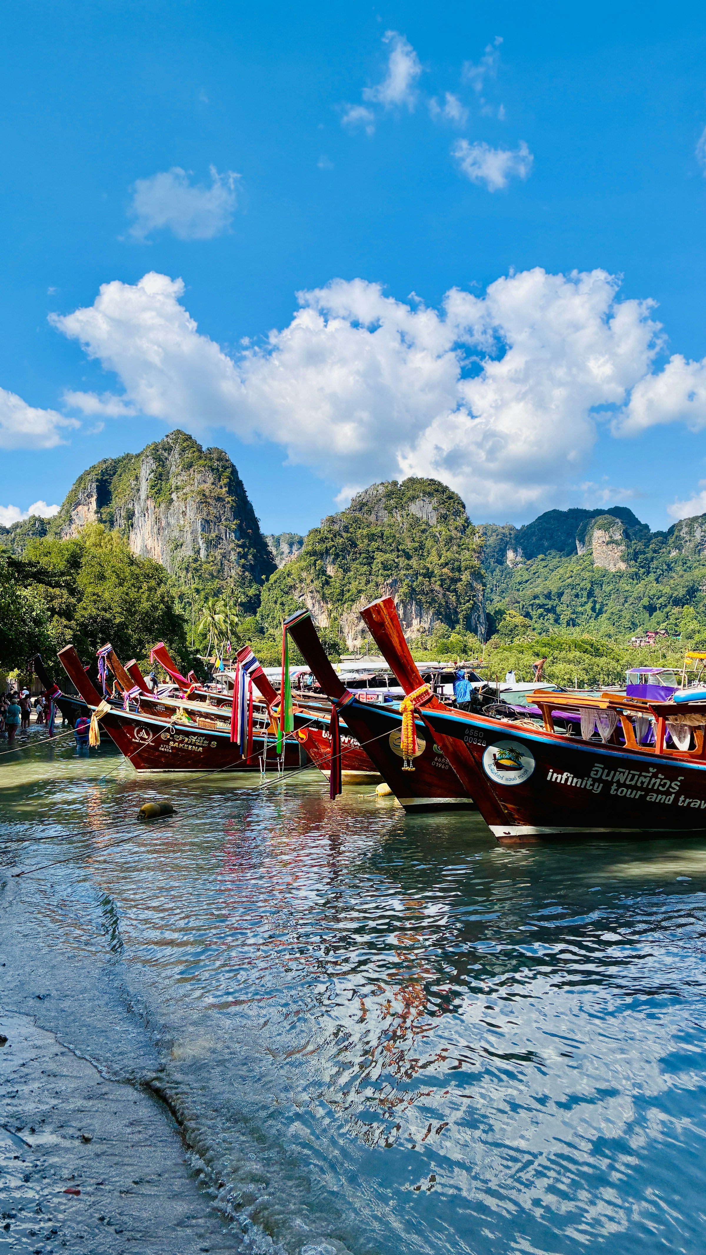 Longtail boats docked by limestone cliffs