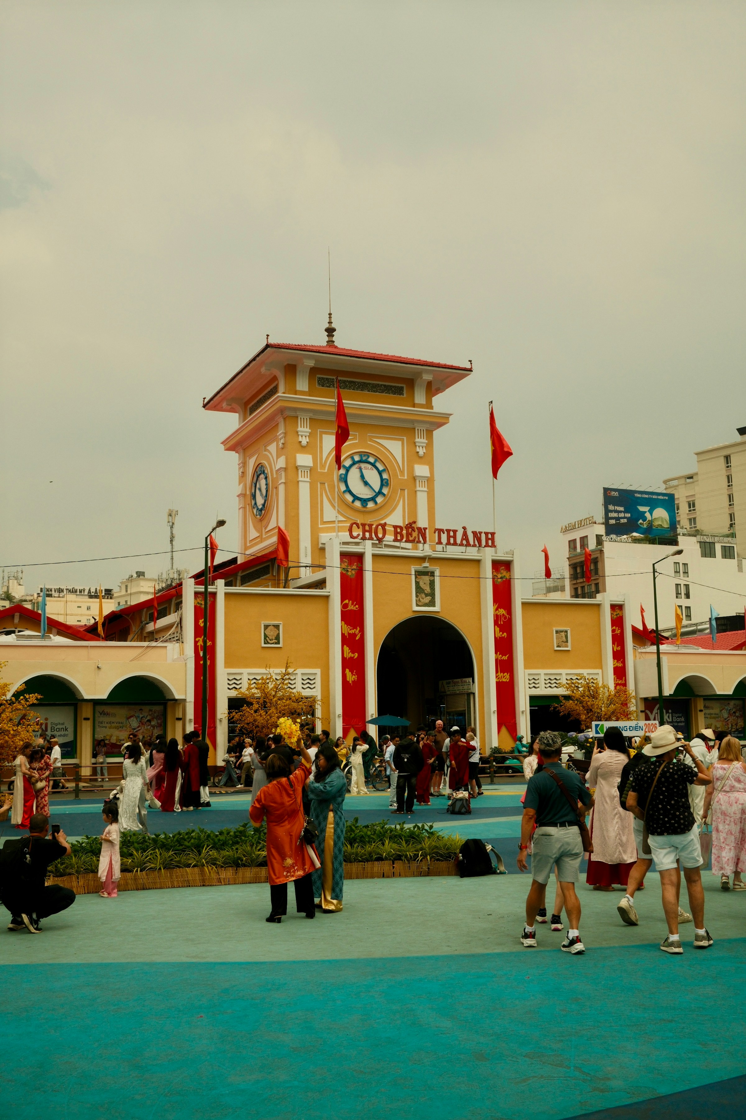Crowds outside a yellow clock tower market entrance, Ben Thanh Market