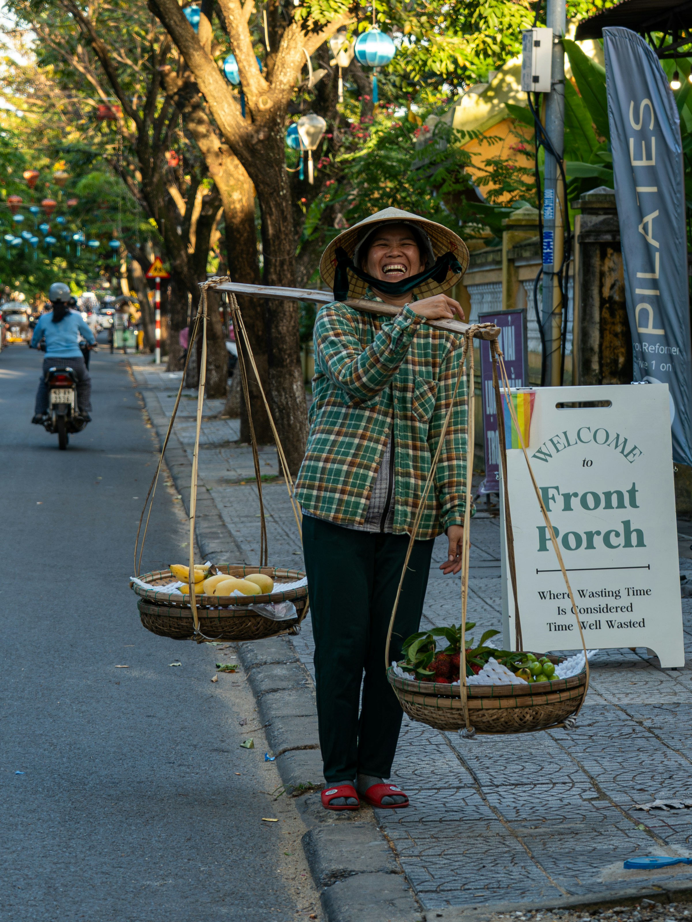 Woman carrying fruit on a shoulder pole, Hoi An market