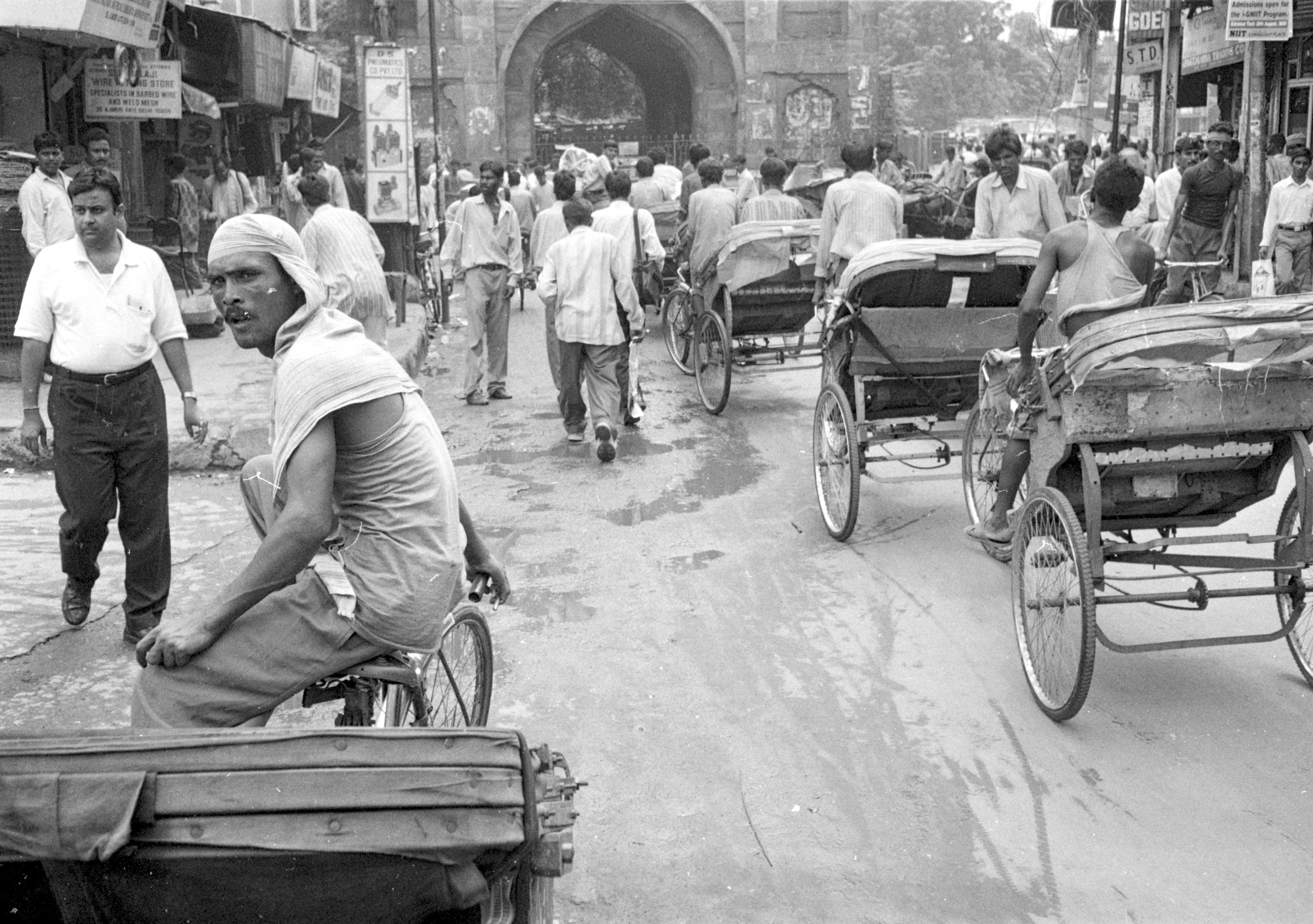 People and cycle rickshaws on a busy street, Old Delhi