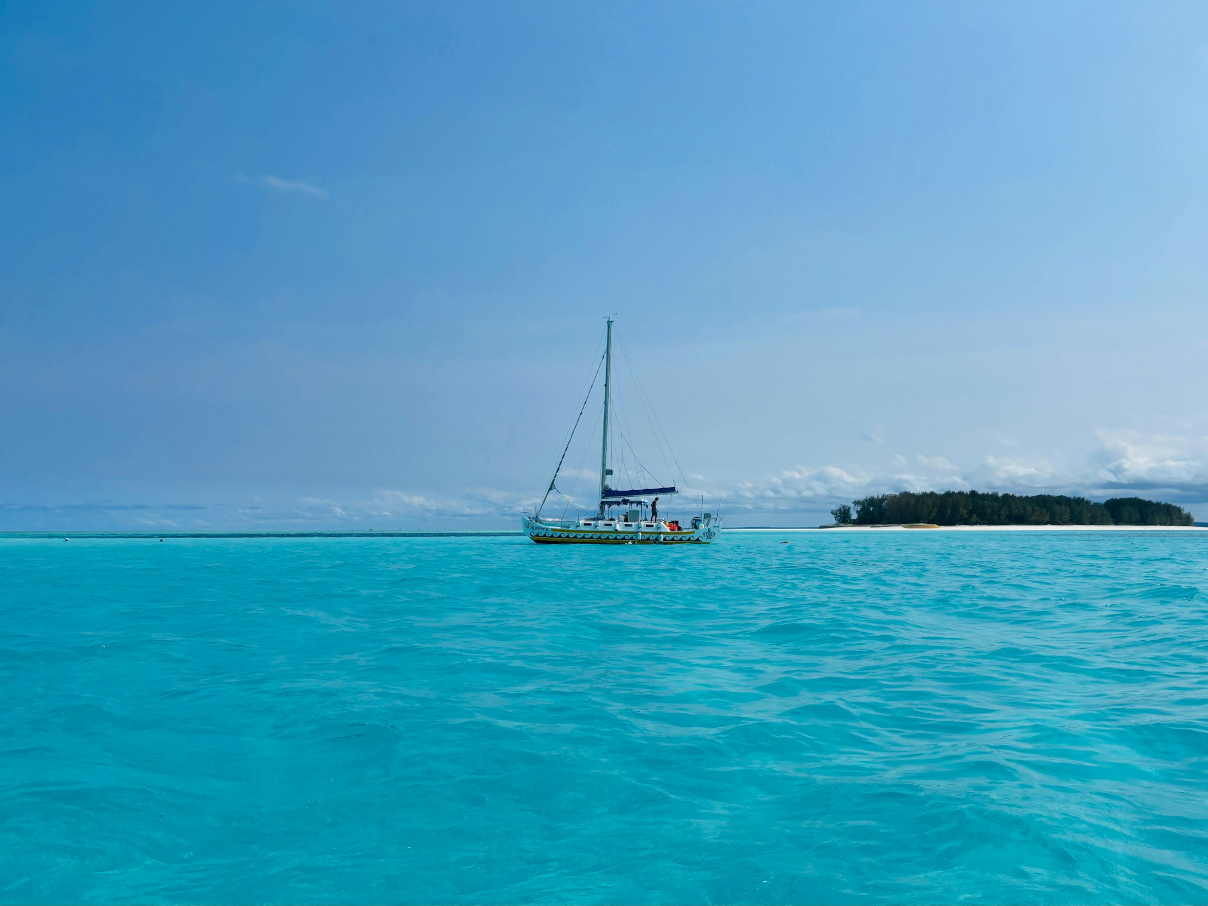 Sailboat on turquoise water near a tropical island, Cham Islands