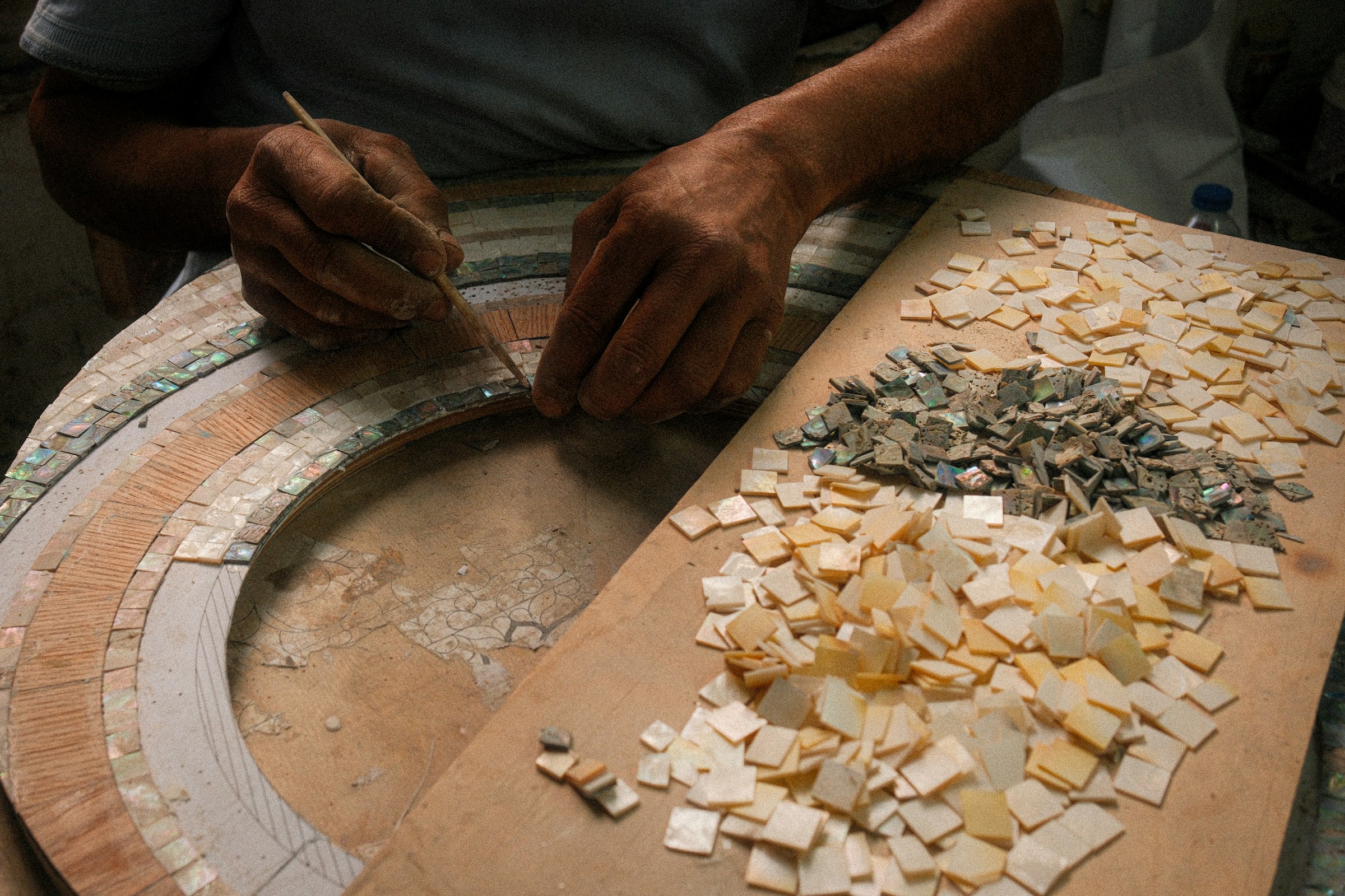 Artisan crafting a mosaic with small tiles, marble inlay workshop
