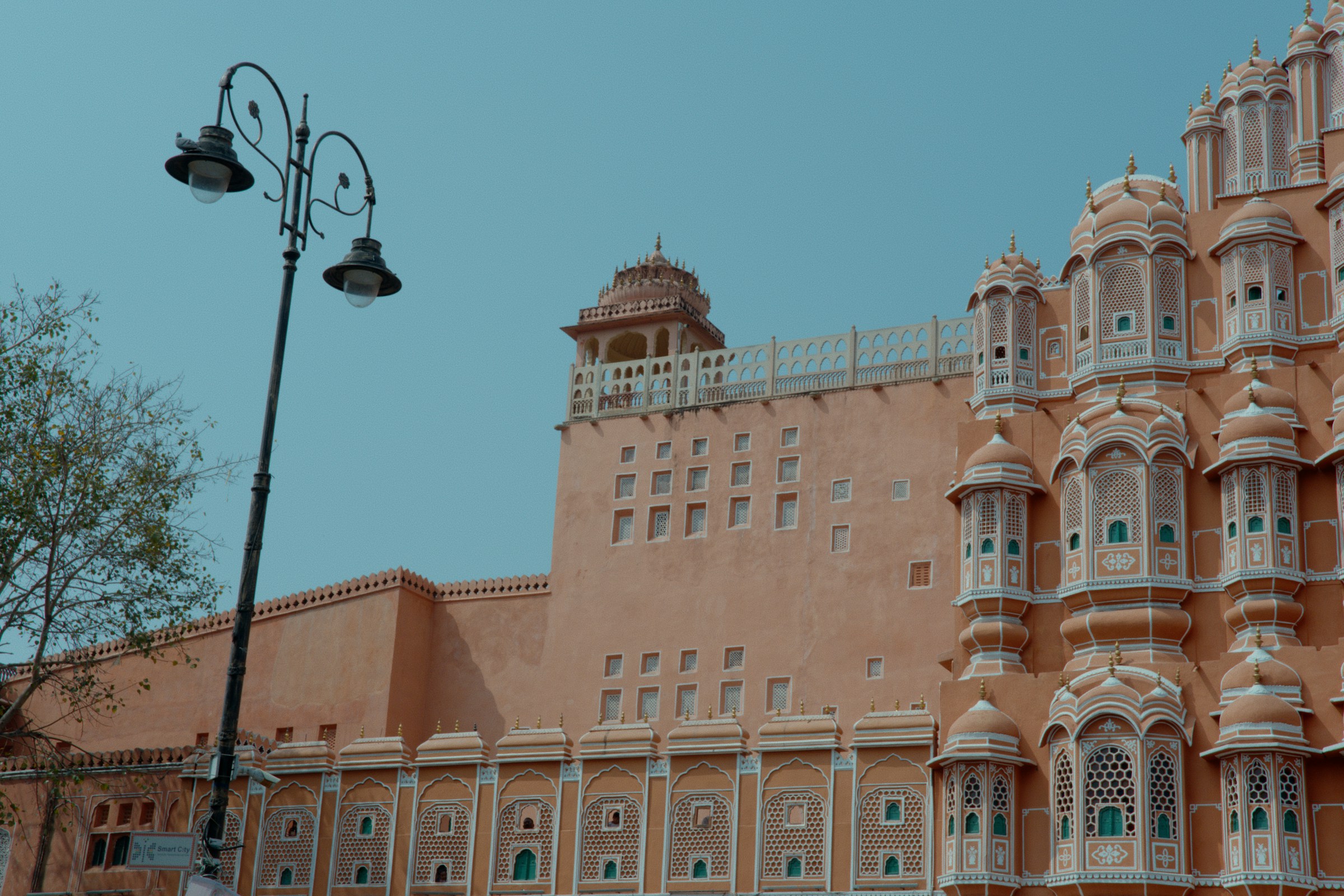 Pink palace with ornate windows and a street lamp