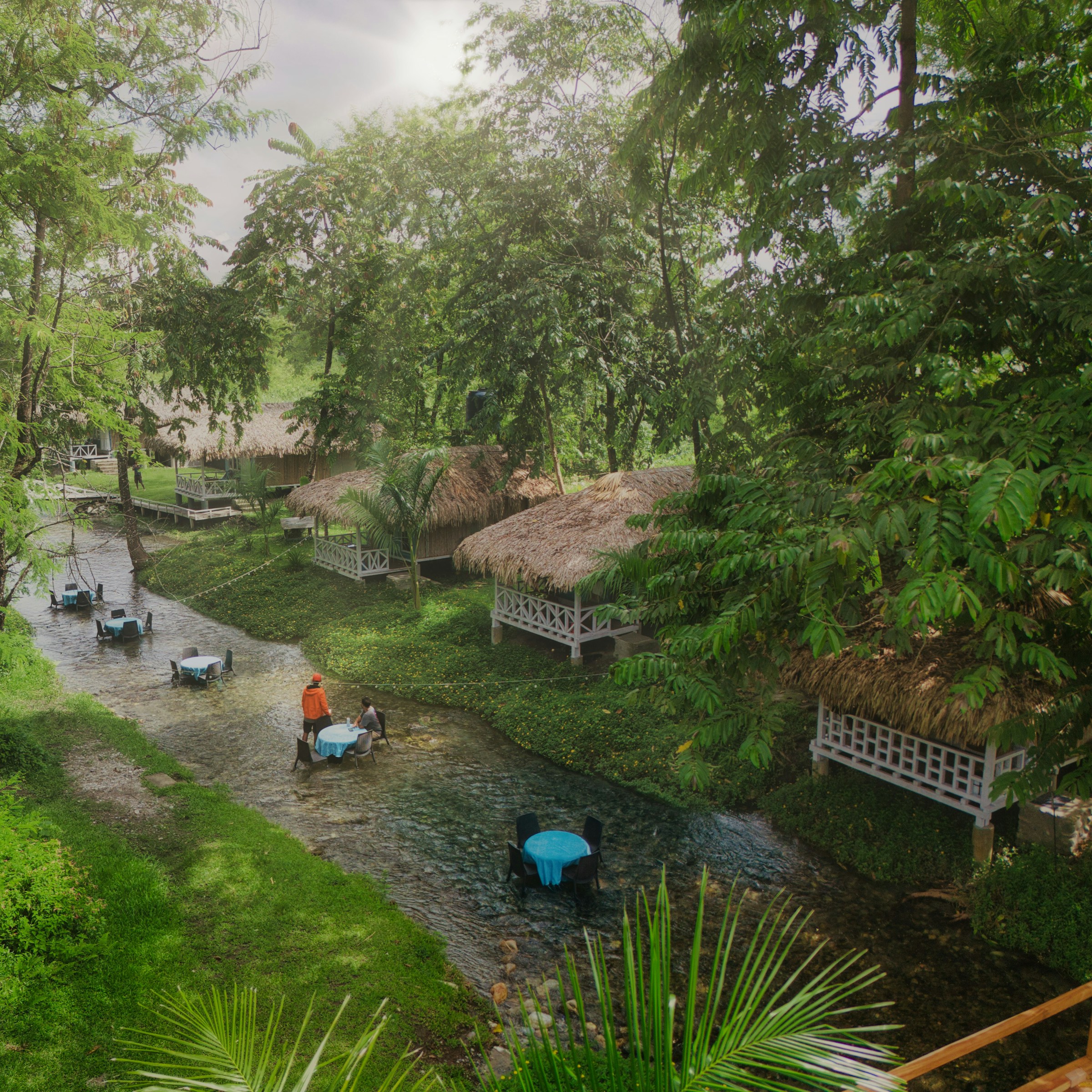 Tropical resort with huts and tables in a stream