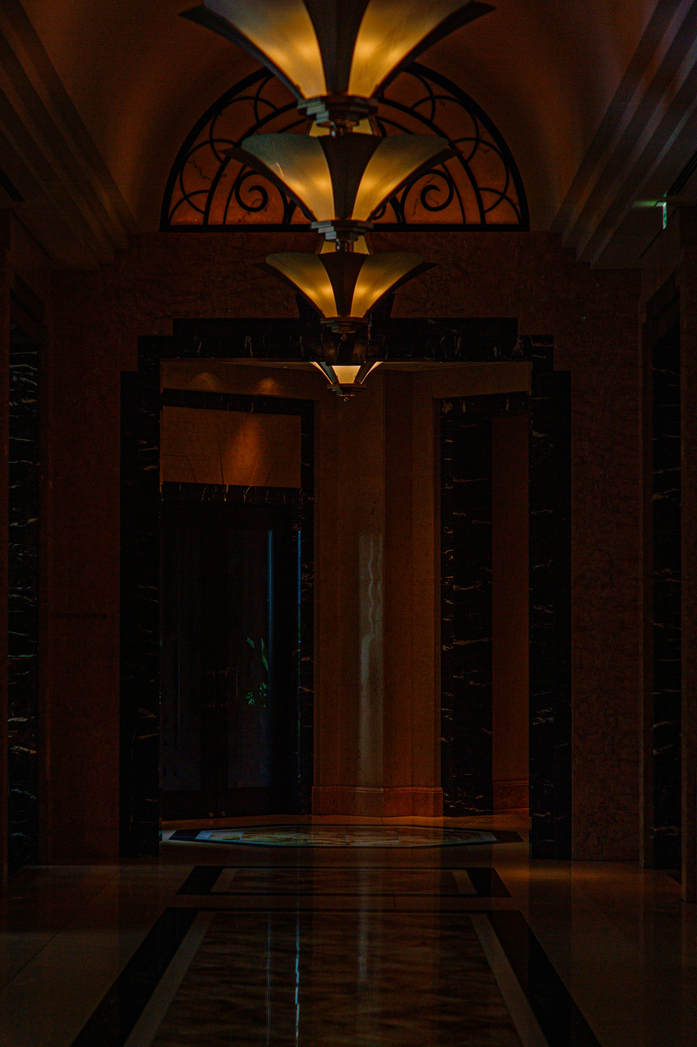 Ornate hotel hallway with decorative ceiling lights and marble floors