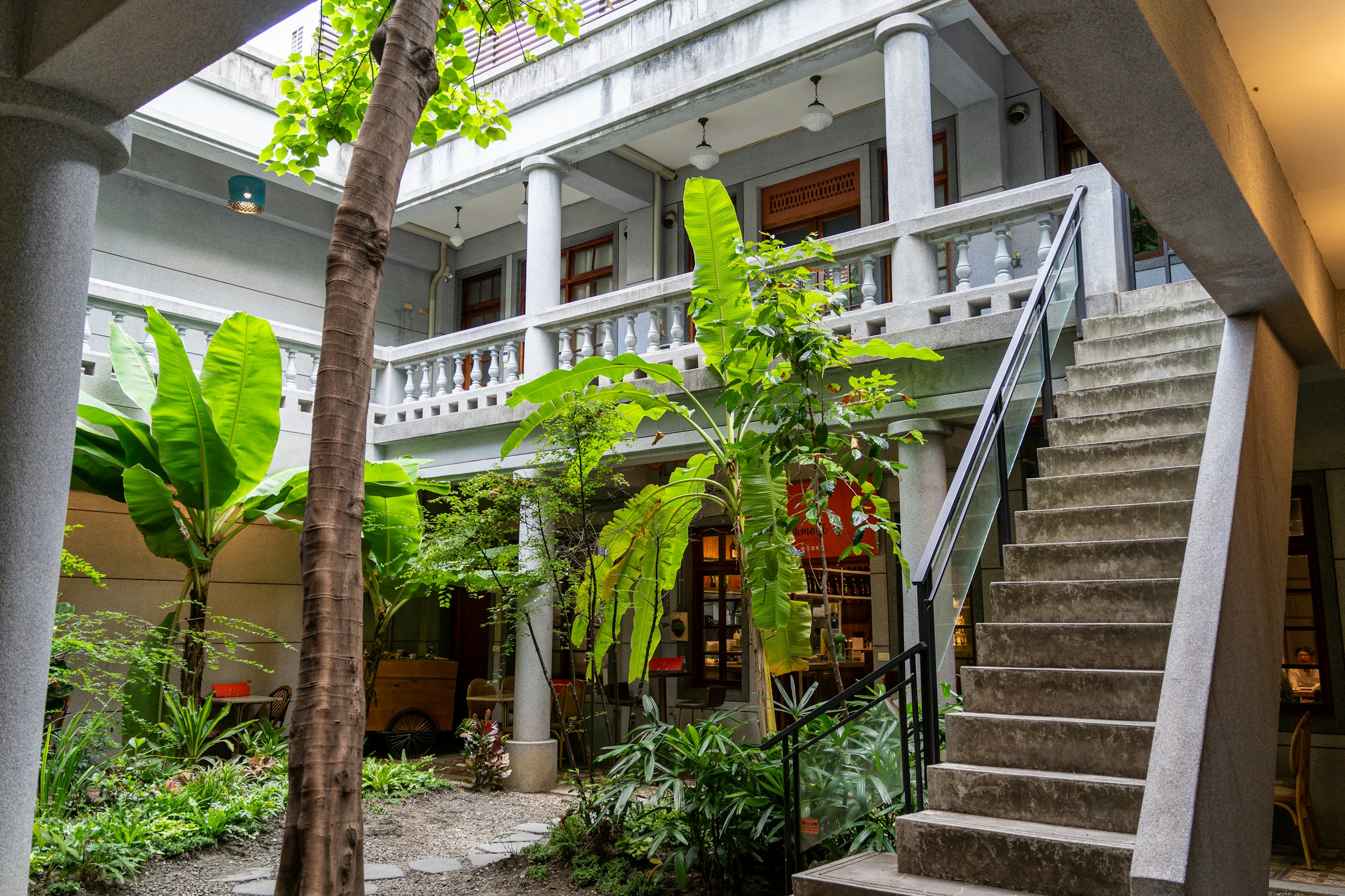 Courtyard with lush greenery and a staircase, riverside hotel